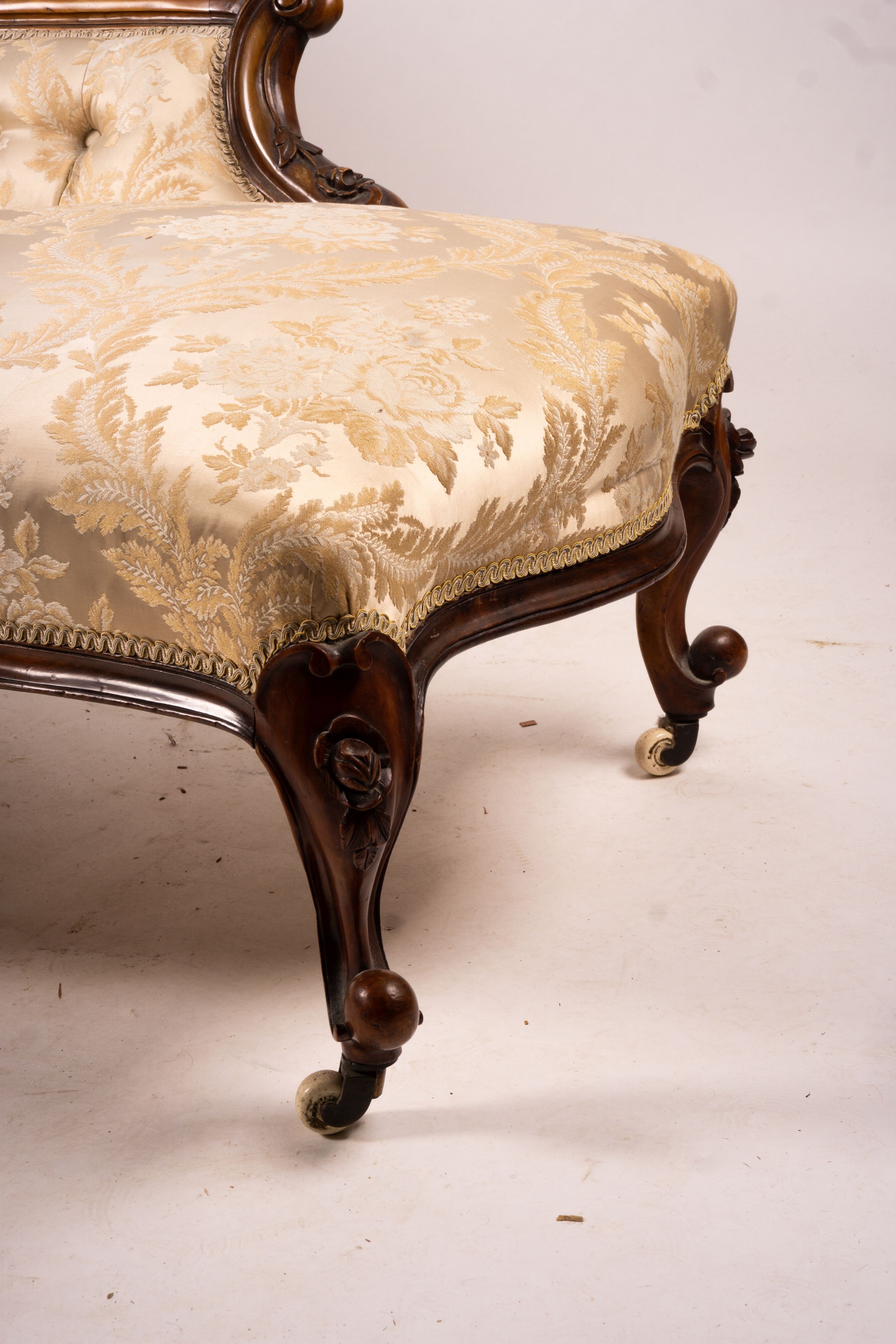 A late Victorian carved walnut three piece salon suite, comprising chaise longue, open armchair and nursing chair